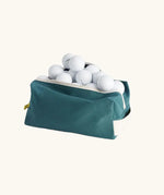 Fluf Traveller Bag in cypress green filled with golf balls, shown with zip open.