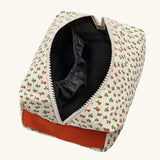 Overhead view of the Fluf Traveller Bag in tiny rose print, a compact organic cotton washbag with orange red carry handle and zip. Zip shown open.