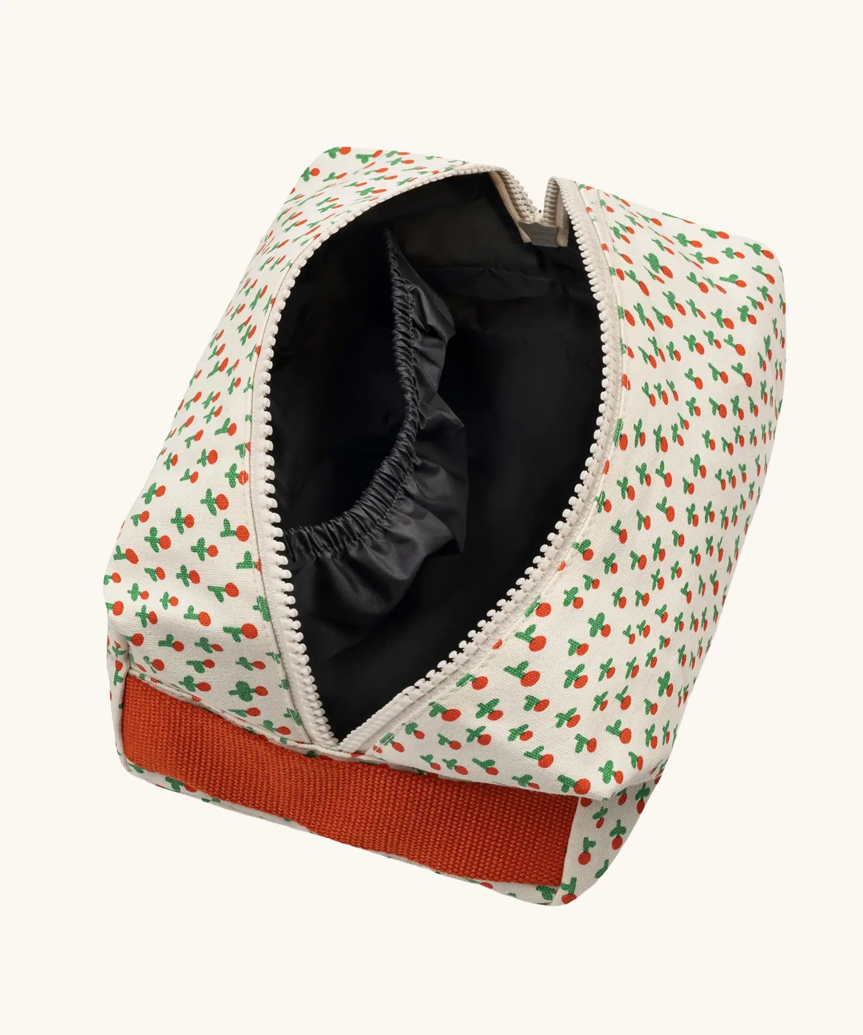 Overhead view of the Fluf Traveller Bag in tiny rose print, a compact organic cotton washbag with orange red carry handle and zip. Zip shown open.