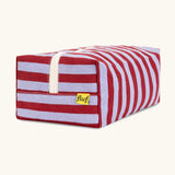 Side view of the Fluf Traveller Bag in Awning Stripe Chili Pepper, showing the striped organic cotton outer, cream zip, and Fluf label.