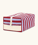 Angled front view of the Fluf Traveller Bag in Awning Stripe Chili Pepper, a compact organic cotton washbag with cream carry handle and zip.
