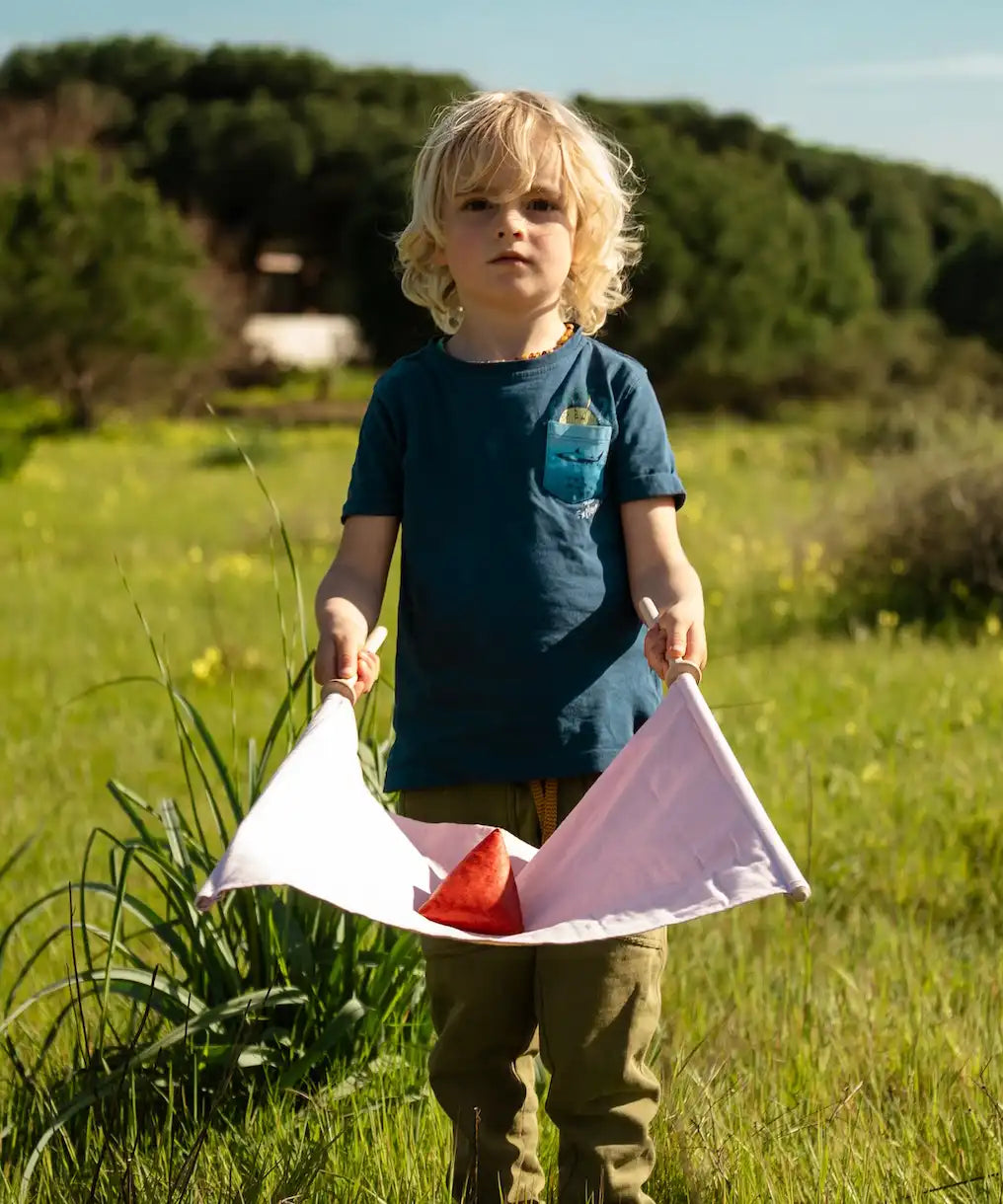 Child holding a fabric sling from the Flup throwing game with the soft throwing bag balanced on it.