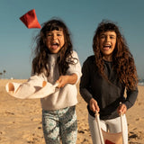 Children playing with the Flup throwing game on the beach. Each child is holding one of the fabric slings. 