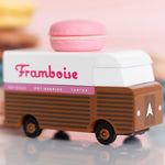 Picture of the Framboise Candylab Candyvan. It is a 1960s style brown and white van with a pink Raspberry Macaron on the roof.