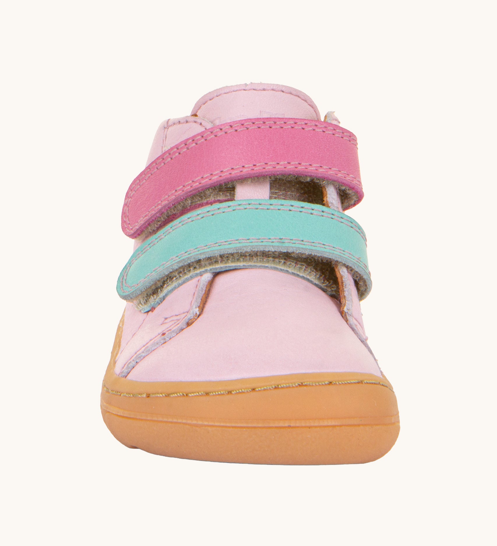 A front on view of the Froddo first step shoes in pink available at Babipur. A soft ankle high natural leather shoe in light pink with 2 velcro straps on the front in dark pink and light blue. Features a light brown rubber grippy sole and a padded ankle support.