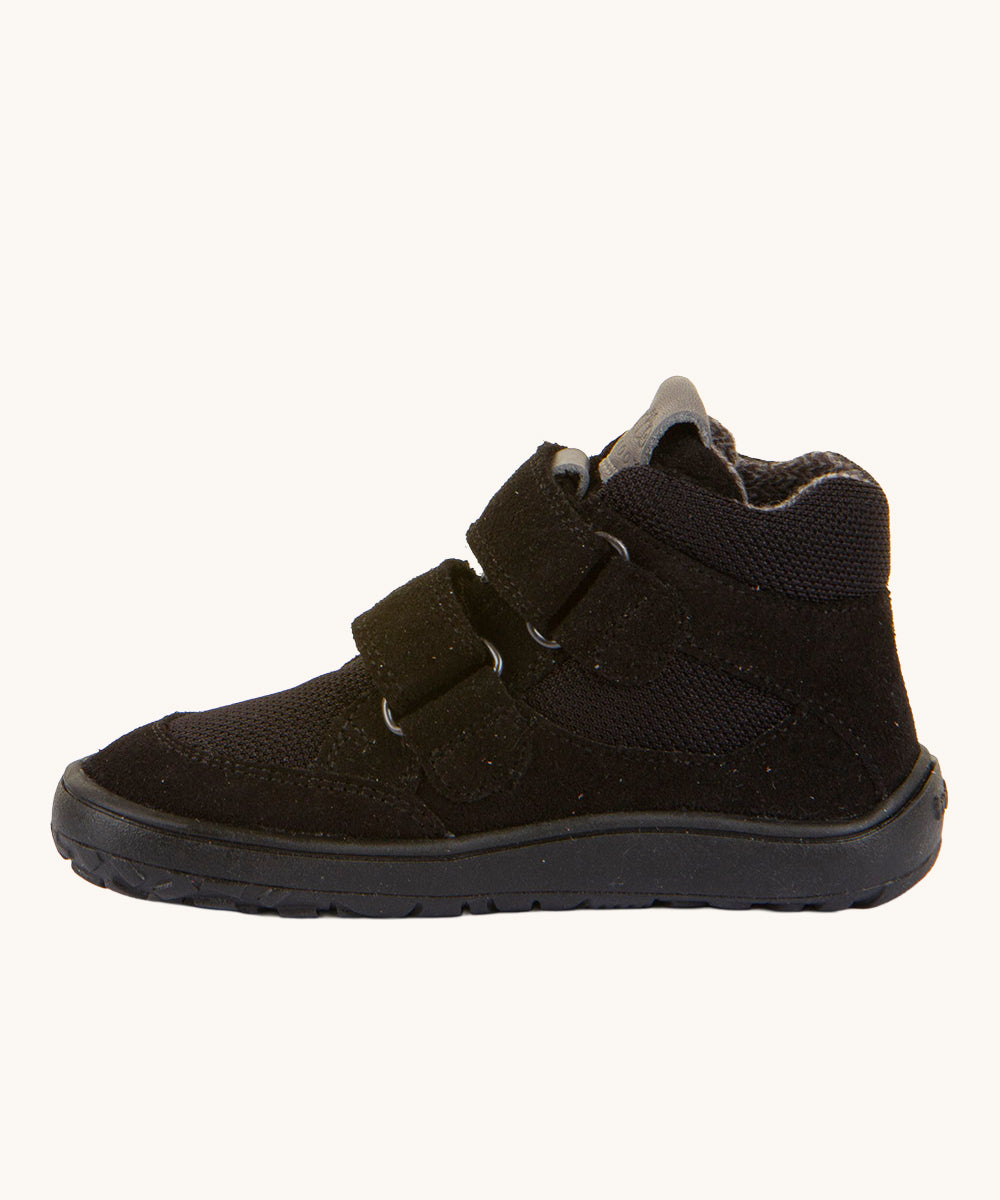 The side of the Froddo Barefoot TEX Kids Autumn Shoes in Black. A soft ankle high shoe in black with a barefoot black rubber sole. Features two velcro straps for a secure fit.  We have a range of children's barefoot shoes available at Babipur. 