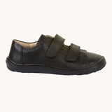A side view of the Froddo Barefoot Black Alex Kids Leather School Shoes. A black leather child's school shoe with two velcro strap fastenings with a barefoot sole. We have a range of children's barefoot shoes available at Babipur. 