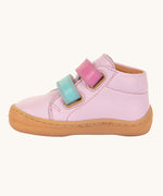 A side profile view of the Froddo first step shoes in pink available at Babipur. A soft ankle high natural leather shoe in light pink with 2 velcro straps on the front in dark pink and light blue. Features a light brown rubber grippy sole and a padded ankle support.