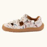 Side of the Froddo barefoot kids sandals in beige with a dinosaur themed outline print.