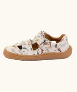 Side of the Froddo barefoot kids sandals in beige with a dinosaur themed outline print.