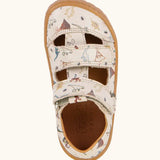 Froddo barefoot kids sandals in beige with a dinosaur themed outline print. Birds eye view.