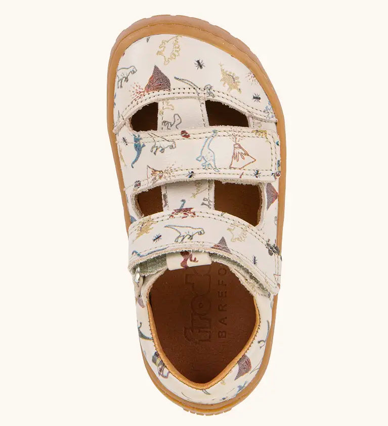 Froddo barefoot kids sandals in beige with a dinosaur themed outline print. Birds eye view.