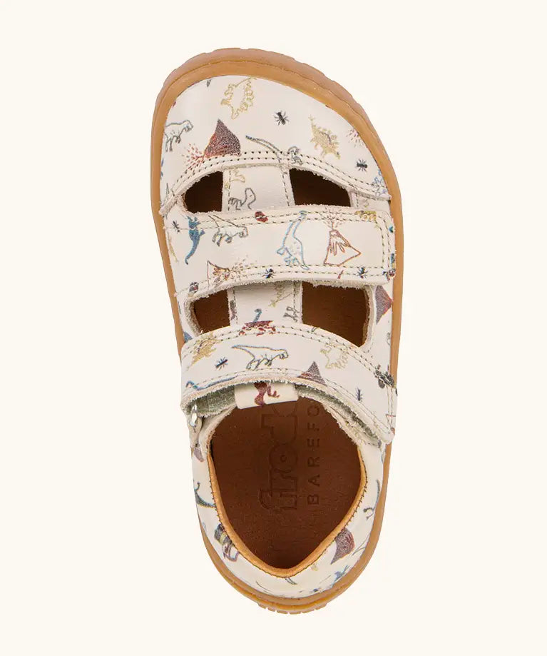 Froddo barefoot kids sandals in beige with a dinosaur themed outline print. Birds eye view.