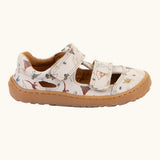 Side of the Froddo barefoot kids sandals in beige with a dinosaur themed outline print.