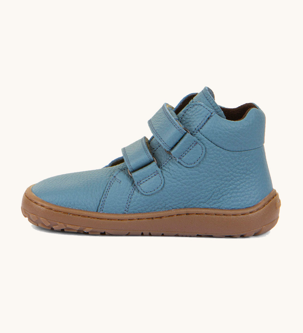 A side image of a Froddo barefoot Autumn children's shoe in light blue jeans colour available at Babipur showing the 2 velcro fastener for a secure fit, padded ankle and the dark brown grippy sole