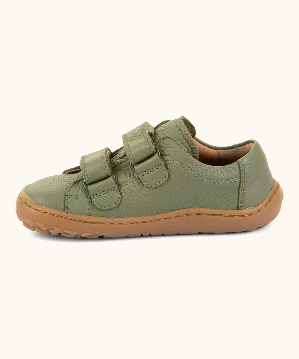 Side of Froddo barefoot base children's shoe in green showing the 2 velcro fasteners looped through and the brown grippy sole