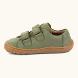 Side of Froddo barefoot base children's shoe in green showing the 2 velcro fasteners looped through and the brown grippy sole
