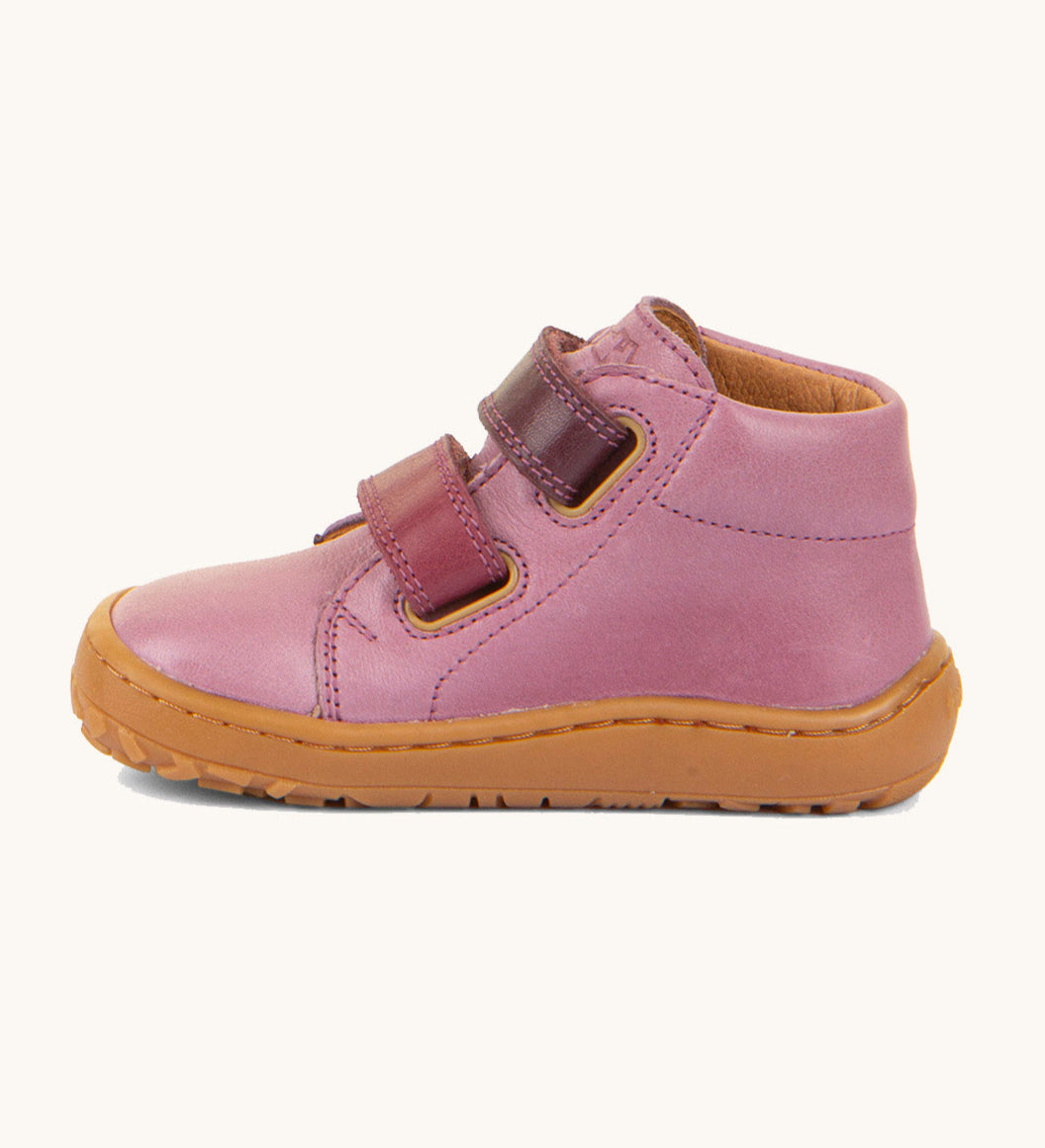 A side image of the Froddo barefoot first step baby shoe in pink available at Babipur. Showing the 2 darker pink velcro fastener for a secure fit and the light brown grippy sole