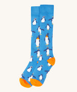 A close up of the Frugi dark blue penguin brilliant boot sock showing the penguin print and orange toe and heel detail on organic cotton fabric