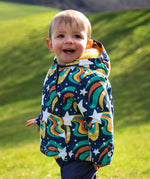 A child wearing the coat from the Frugi 2 in 1 rambler pram suit to coat in magic stars. A thick warm hooded coat with a yellow fleece inner for warmth 