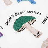 A close up of the green cracking russula fungi on the Frugi Children's Organic Ace Applique Top - White / Mushrooms.