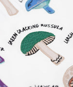 A close up of the green cracking russula fungi on the Frugi Children's Organic Ace Applique Top - White / Mushrooms.