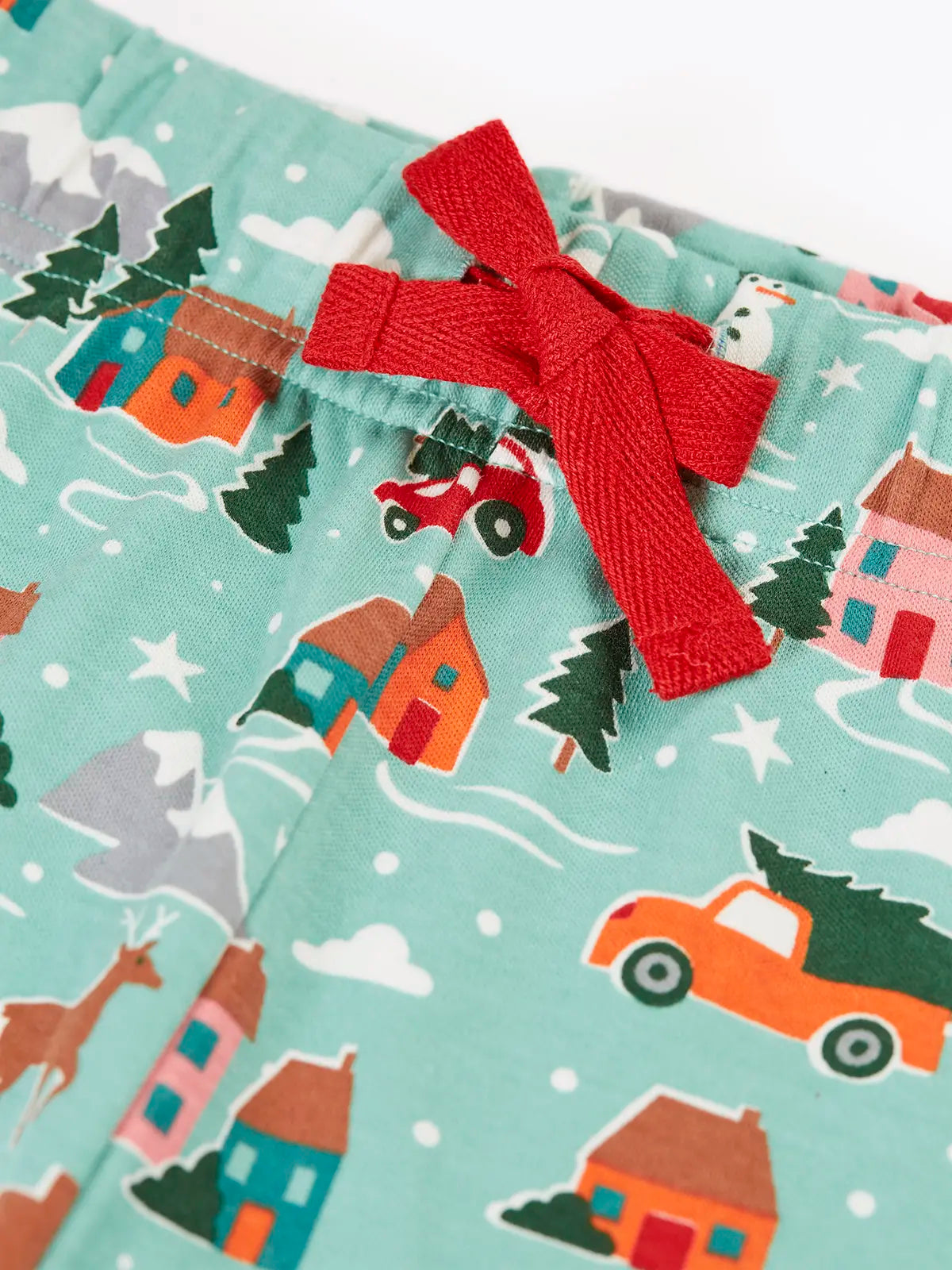 Close up of the red waist tie on the Frugi adults organic cotton perranporth pyjamas with a festive winter drives print on a light moss green background. 