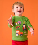 Child wearing the Frugi adventure applique organic cotton long sleeved kids' top in a palm green with tractor appliques on the front.