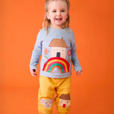 Child wearing the Frugi's GOTS 100% organic cotton top in light blue showing the cute house on a rainbow applique on the front with matching yellow character applique joggers. 