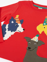 Close up of the front of the Frugi organic cotton adventure circular long sleeve top scarlet red with three dogs wearing party hats on the front. 