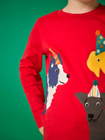 Close up of a child wearing the Frugi organic cotton adventure circular long sleeve top scarlet red with three dogs wearing party hats on the front. 