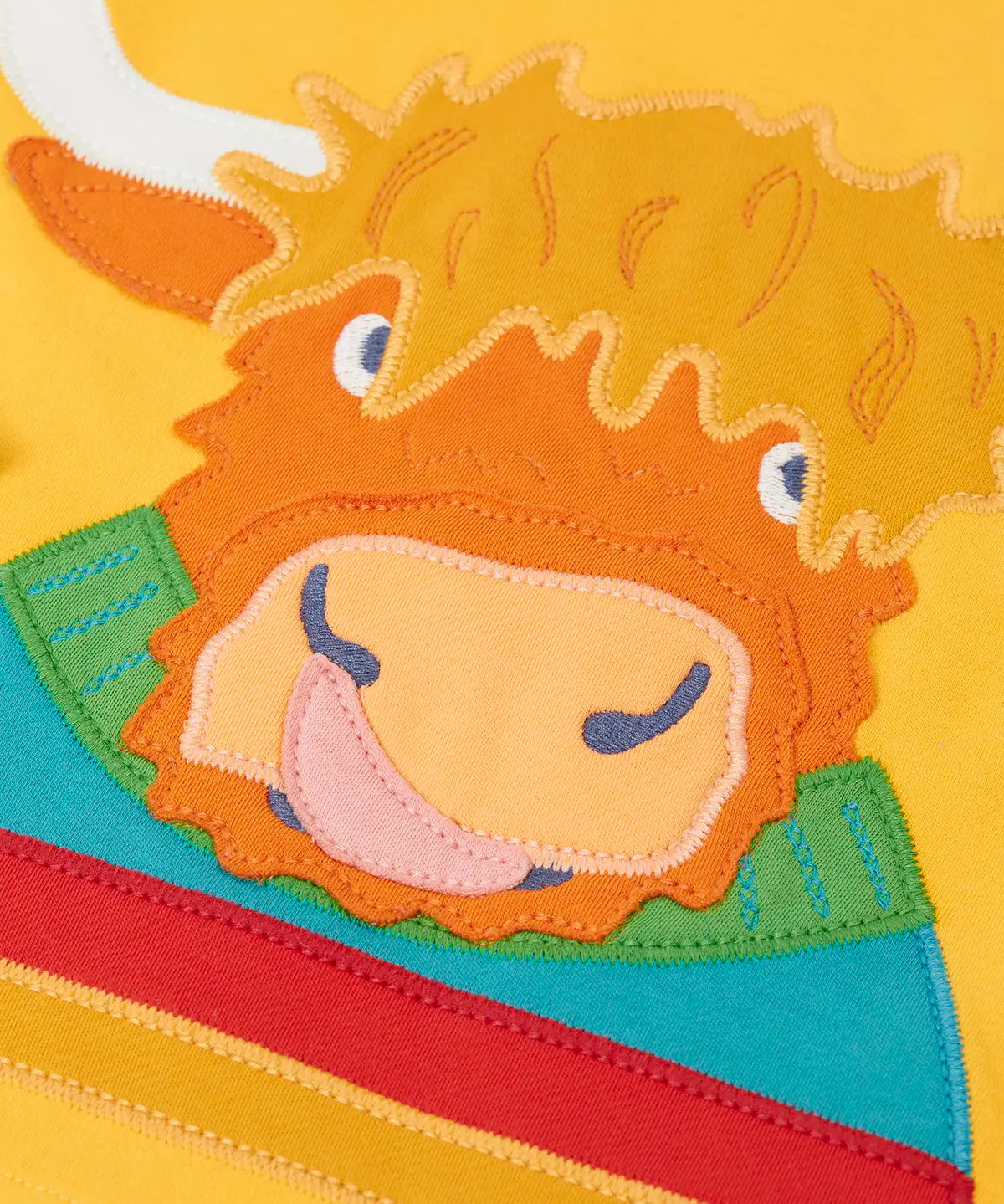 Close up of the Highland cow coo applique on the Frugi adventure circular cotton top in bumblebee yellow.