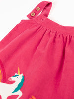 Close up of the two position button closure on the straps of the Frugi agatha organic cotton pink corduroy pinafore child's dress with unicorn applique.