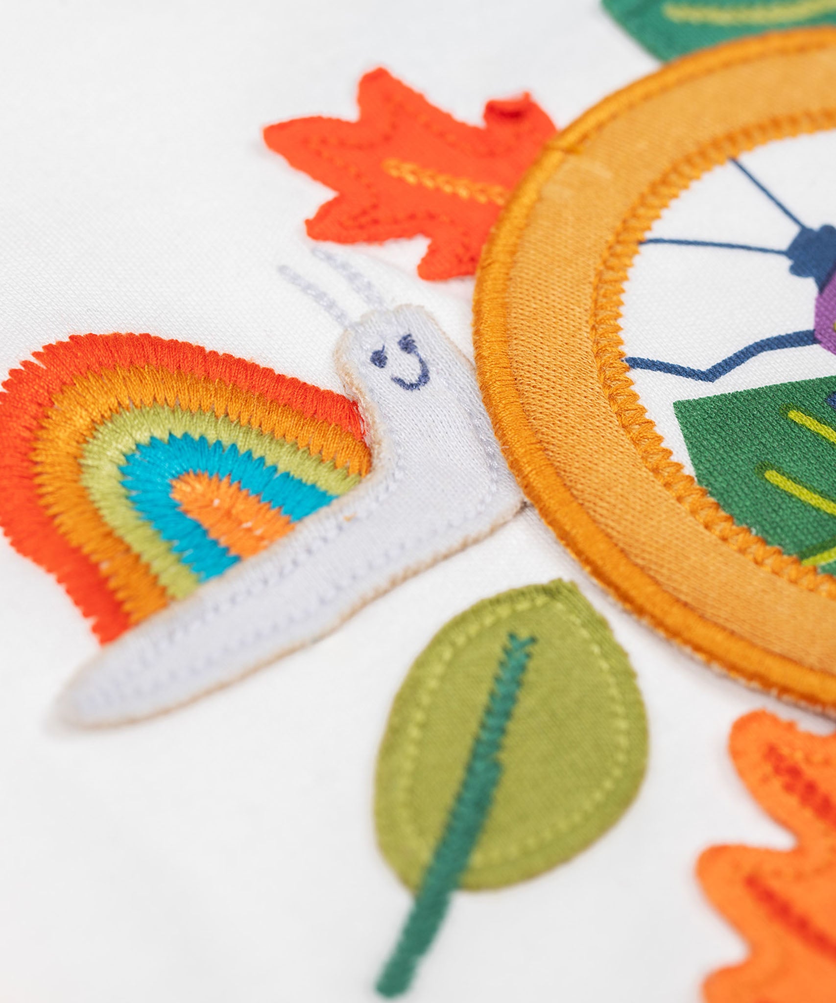 A close up of the snail embroidered snail applique Frugi organic cotton Alfie interactive long sleeved top.