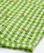 Close up of the Frugi kids Alfred dungarees outfit showing the orange carrot embroidery and leg cuff detail on green gingham organic cotton fabric