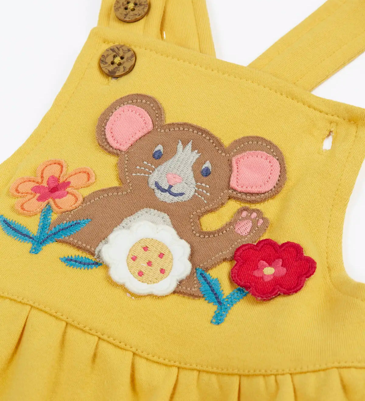 Close up of the mouse and flowers applique on the front of the Frugi Ania bumblebee yellow organic cotton pinafore dress.