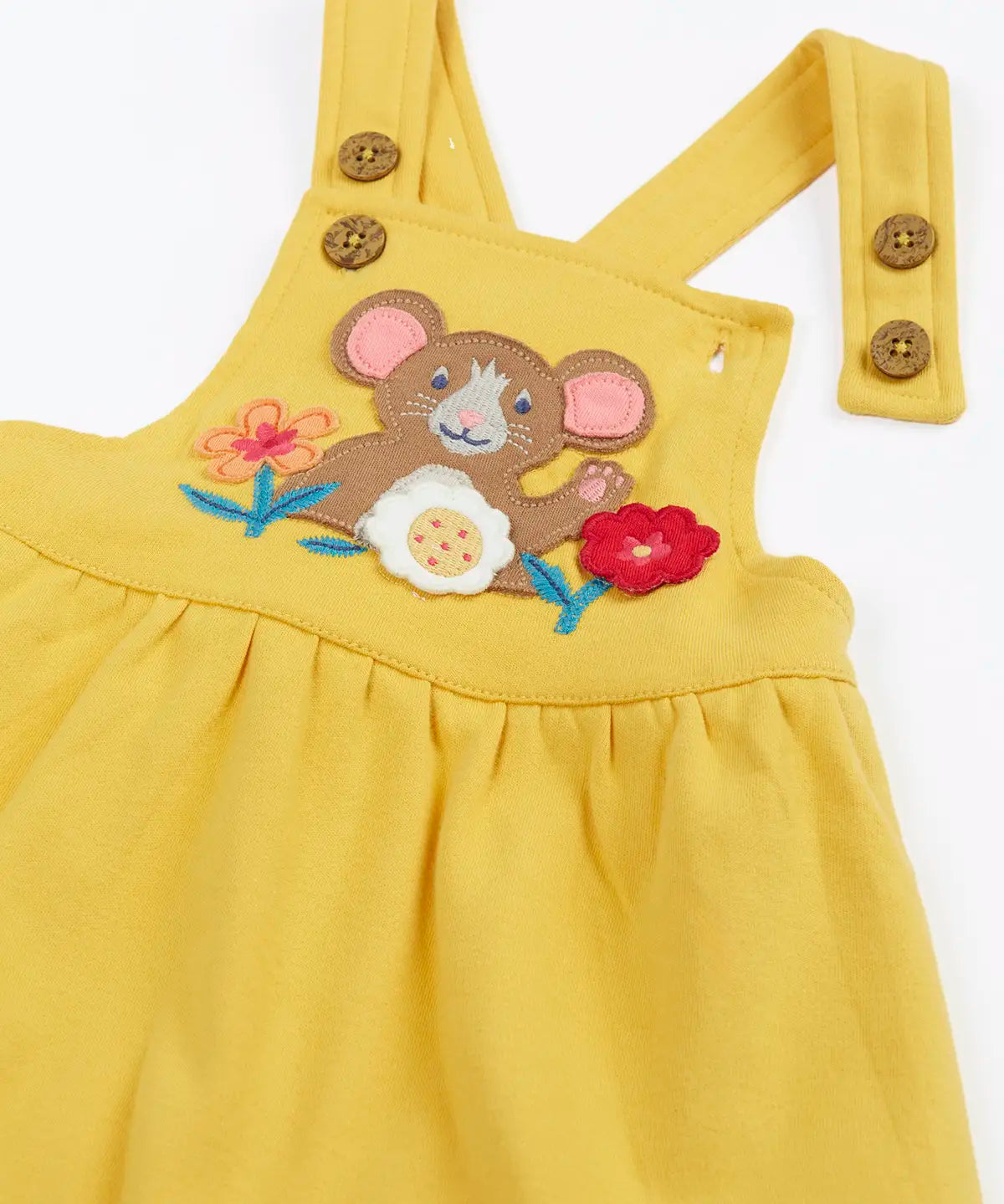 Close up of the front of the Frugi Ania bumblebee yellow pinafore dress with mouse and flowers applique on the front.