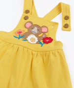Close up of the front of the Frugi Ania bumblebee yellow pinafore dress with mouse and flowers applique on the front.