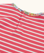 Close up of the popper closure on the back of the Frugi Archer horse and cat applique top in a pink rhubarb Breton stripe .