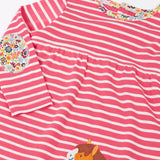 Close up of the floral neckline trim and elbow patch on the Frugi archer dress in rhubarb pink Breton stripes with horse and cat pals appliques along the hemline.