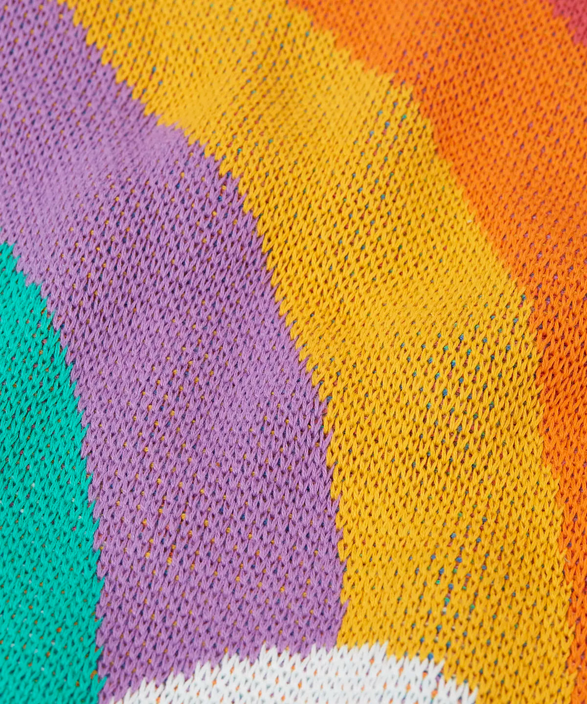 Close up of the knit on the Frugi Aubrey organic cotton knitted jumper with a hotchpotch rainbow design.