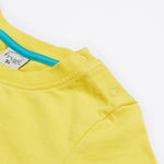 A close up of Frugi Avery Appligue T-Shirt in Welly Yellow, featuring a popper fastenings.