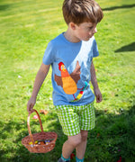 A child wearing the Frugi Avery appliqué t-shirt, a soft GOTS organic cotton light blue top with a chicken riding a skateboard appliqué on the front. 