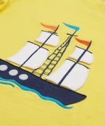 A close up of Frugi Avery Appligue T-Shirt in Welly Yellow, with a Tall Ship embroidered design in the centre.