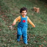 A child running on grass wearing the blue Frugi Babipur cord dungarees. 