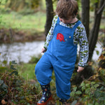 A child walking near a river wearing the blue Frugi Babipur cord dungarees. 