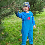 A child standing besides a tree wearing the blue Frugi Babipur cord dungarees.