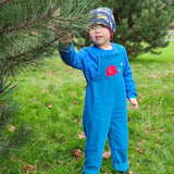 A child standing besides a tree wearing the blue Frugi Babipur cord dungarees.