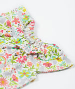Close up of the Frugi baby peony bunny bounce playsuit. Showing the gentle ruffle on the neck on white with bunnies and coloured flowers printed organic cotton fabric.
