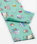 A close up of the Frugi kids let's bake libby leggings. Showing the different cakes, puddings and ice creams design leg cuffs on a light green organic cotton fabric